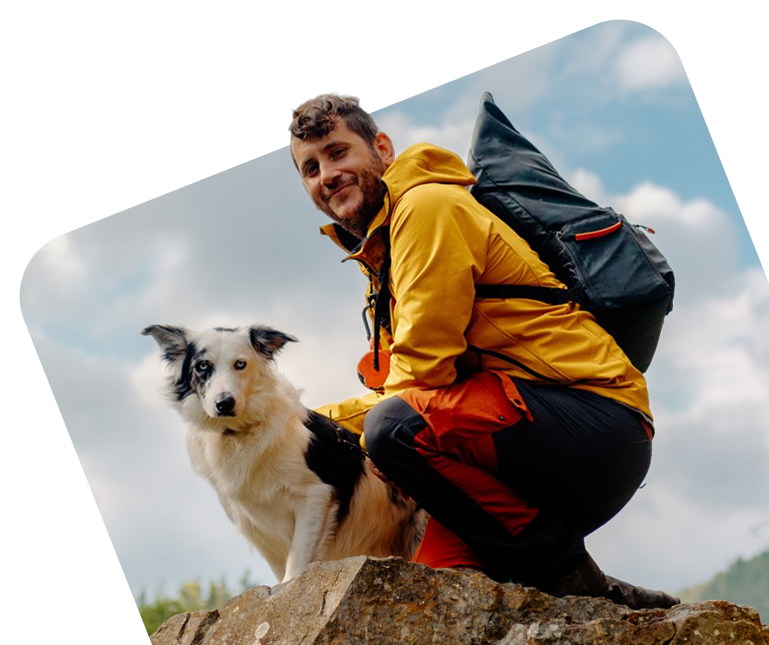 Person lying on a rock with their dog, looking at the user